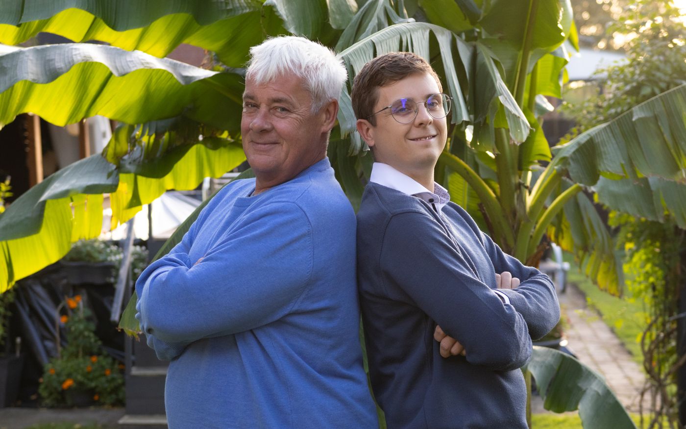 Thomas und Marius Mersch stehen Rücken an Rücken im Garten